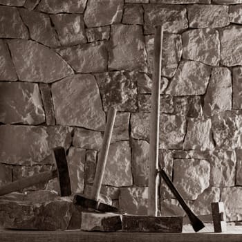 Hammer mason tools of stonecutter masonry work in a contruction stone wall