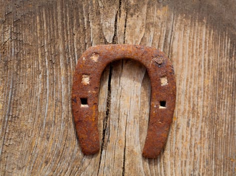 Antique horseshoe luck symbol rusted on vintage wood background