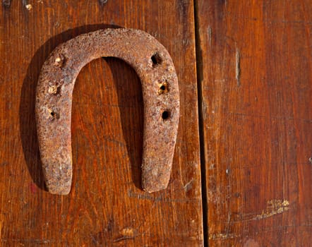 Antique horseshoe luck symbol rusted on vintage wood background