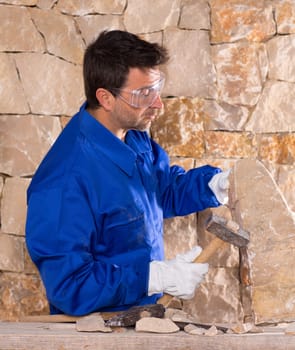 Masonry mason stonecutter man with hammer working on stone wall construction