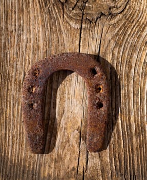 Antique horseshoe luck symbol rusted on vintage wood background