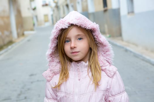 Child girl tourist walking in traditional Spain village pink winter fur hood
