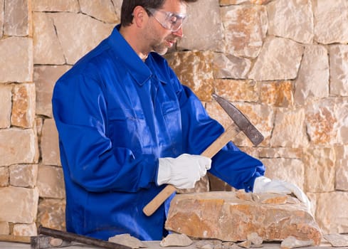 Masonry mason stonecutter man with hammer working on stone wall construction