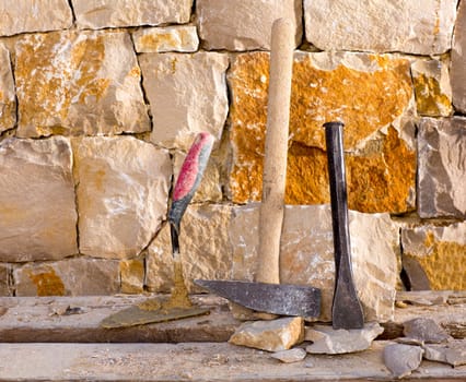 Hammer mason tools of stonecutter masonry work in a contruction stone wall