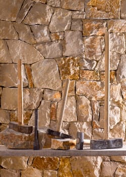 Hammer mason tools of stonecutter masonry work in a contruction stone wall