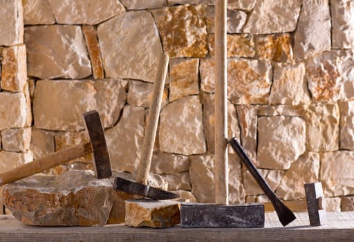 Hammer mason tools of stonecutter masonry work in a contruction stone wall