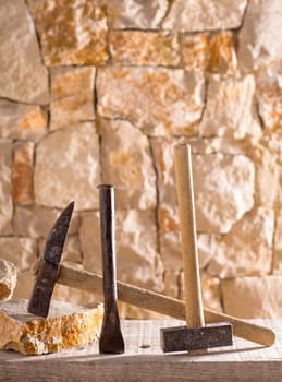 Hammer mason tools of stonecutter masonry work in a contruction stone wall