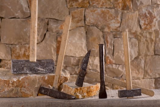 Hammer mason tools of stonecutter masonry work in a contruction stone wall
