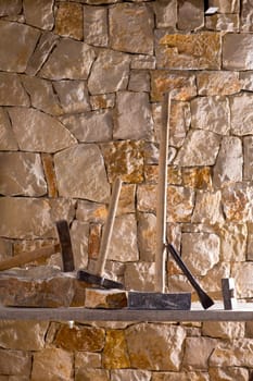 Hammer mason tools of stonecutter masonry work in a contruction stone wall