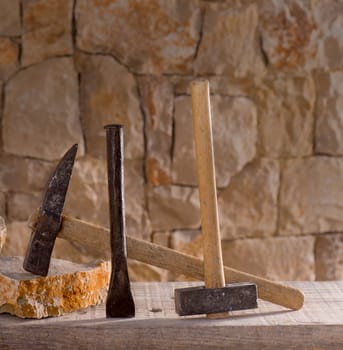 Hammer mason tools of stonecutter masonry work in a contruction stone wall