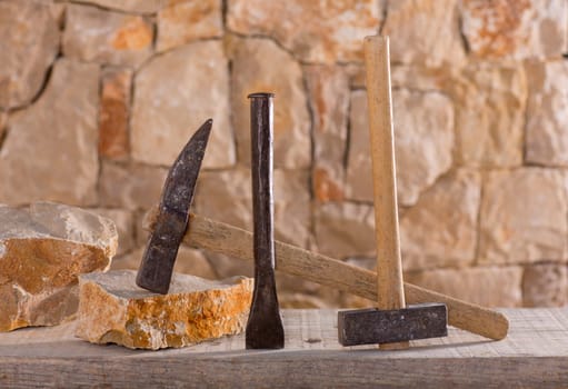 Hammer mason tools of stonecutter masonry work in a contruction stone wall