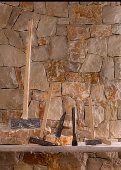 Hammer mason tools of stonecutter masonry work in a contruction stone wall