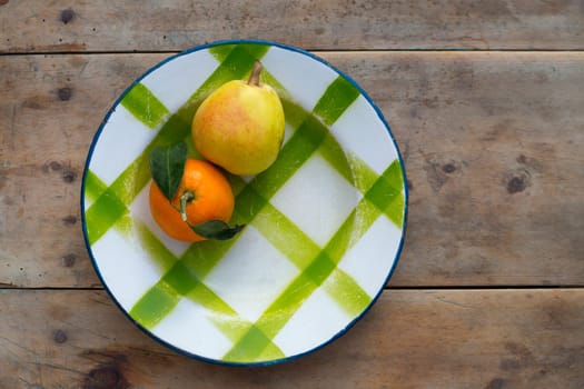 fruits tangerine and pear in vintage porcelain dish plate on retro wood table