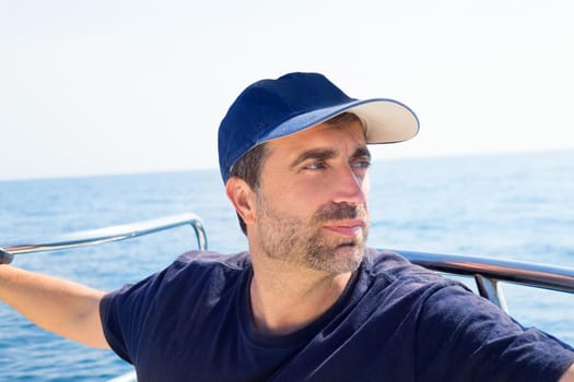 Sailor man at boat bow with cap looking away the sea while sailing