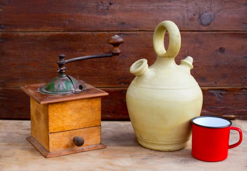 retro old coffee grinder with vintage botijo clay jar on aged wood