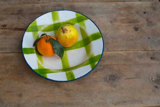 fruits tangerine and pear in vintage porcelain dish plate on retro wood table
