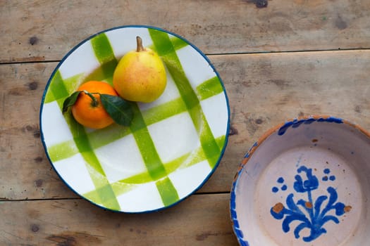 fruits tangerine and pear in vintage porcelain dish plate on retro wood table