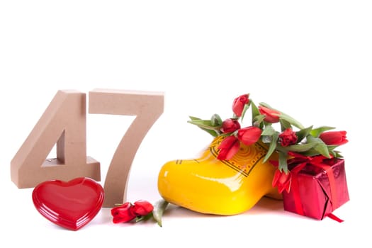 Number of age in a colorful studio setting and Dutch looking attributes like a clog woonden shoe and tulips