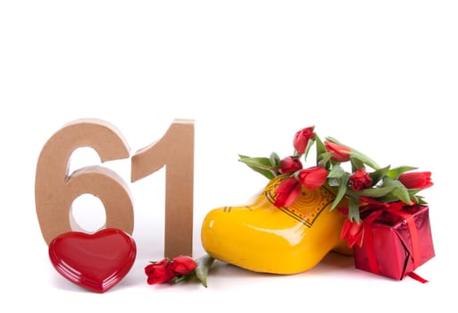 Number of age in a colorful studio setting and Dutch looking attributes like a clog woonden shoe and tulips