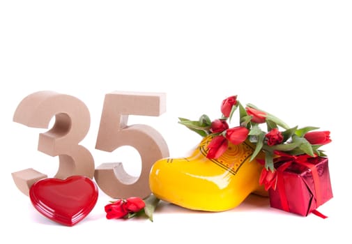 Number of age in a colorful studio setting and Dutch looking attributes like a clog woonden shoe and tulips
