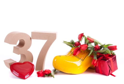 Number of age in a colorful studio setting and Dutch looking attributes like a clog woonden shoe and tulips
