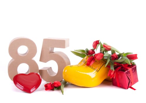 Number of age in a colorful studio setting and Dutch looking attributes like a clog woonden shoe and tulips
