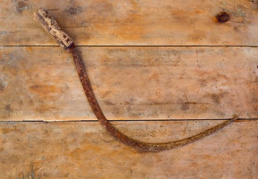 Antique sickle hand tool rusted on aged vintage retro wood