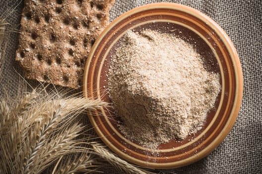 Wholemeal flour and wheat on cloth sack, close-up
