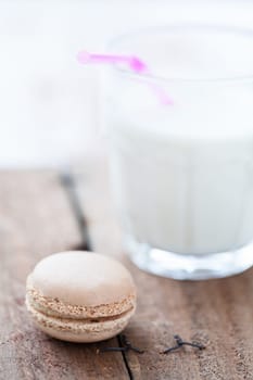 Closeup of macaroon and glass of milk on wooden table