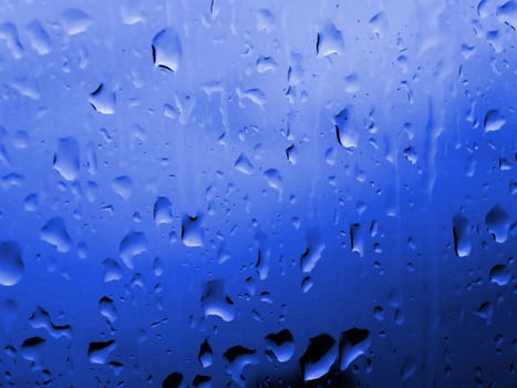 Raindrops on a window with blue light