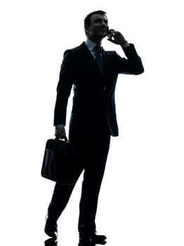 one caucasian businessman walking on the telephone in silhouette studio isolated on white background