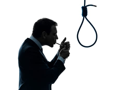 one caucasian man smoking cigarette  standing in front of hangmans noose in silhouette studio isolated on white background