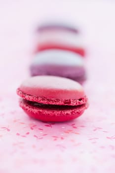 Closeup of row of sweet macaroons on pink mat
