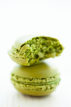 Closeup of one full and one half eaten green pistachio macaroon