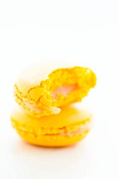 Closeup of one full and one half eaten yellow lemon macaroon