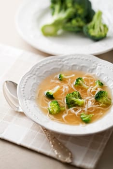Chicken soup with noodles and broccoli close up