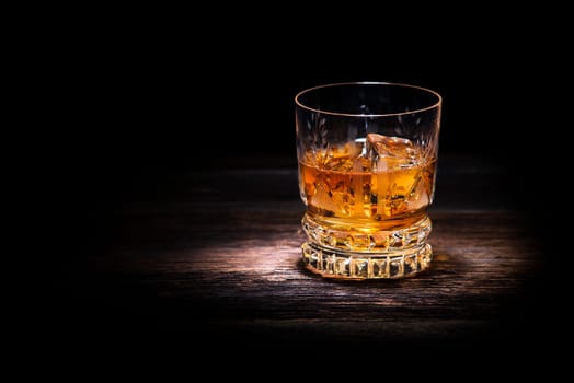 Glass of whiskey on wooden background close up