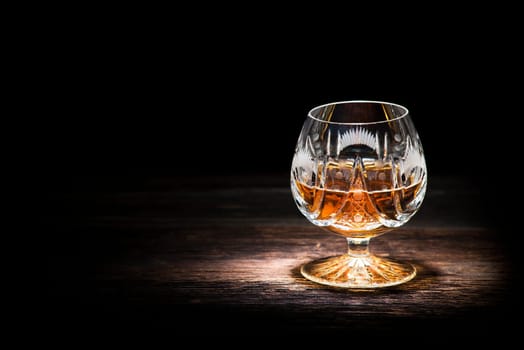 Cognac in crystal glass on wooden background