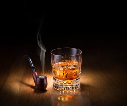 Whiskey and smoking pipe on wooden background
