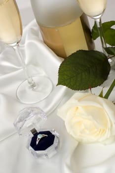 engagement ring with white rose and champagne in background