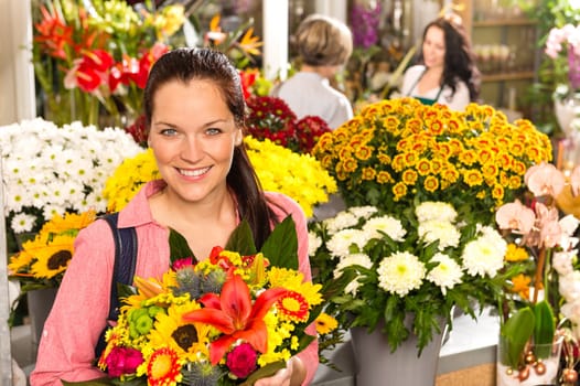 Cheerful florist woman showing colorful flowers market shop retail