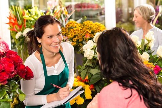 Happy florist writing flower shop talking customer woman