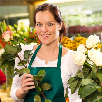 Smiling florist cutting rose flower shop young woman
