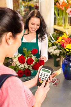 Woman florist selling flowers customer paying credit card red roses