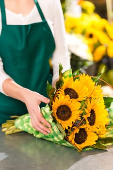 Florist preparing sunflowers bouquet flower shop assistant yellow hands