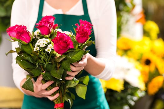 Florist hands showing red roses bouquet flowers shop market