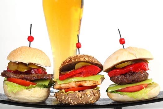 Three hamburgers on plate with glass of beer
