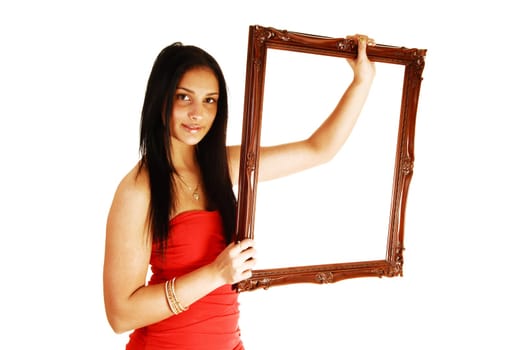 A lovely young teen girl in a red dress, holding up a picture frame with her long black hair standing in the studio for white background.