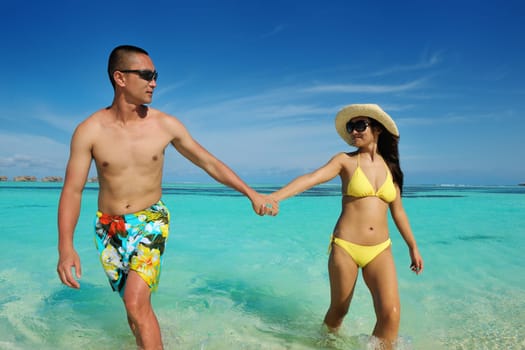 happy young asian couple enjoying summer and have on beautiful white sand beach