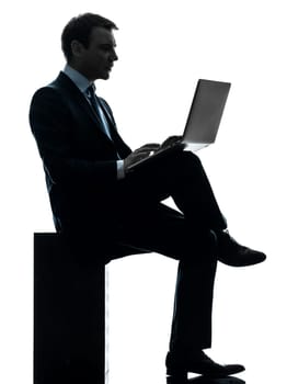 one caucasian businessman computing laptop computer  in silhouette studio isolated on white background